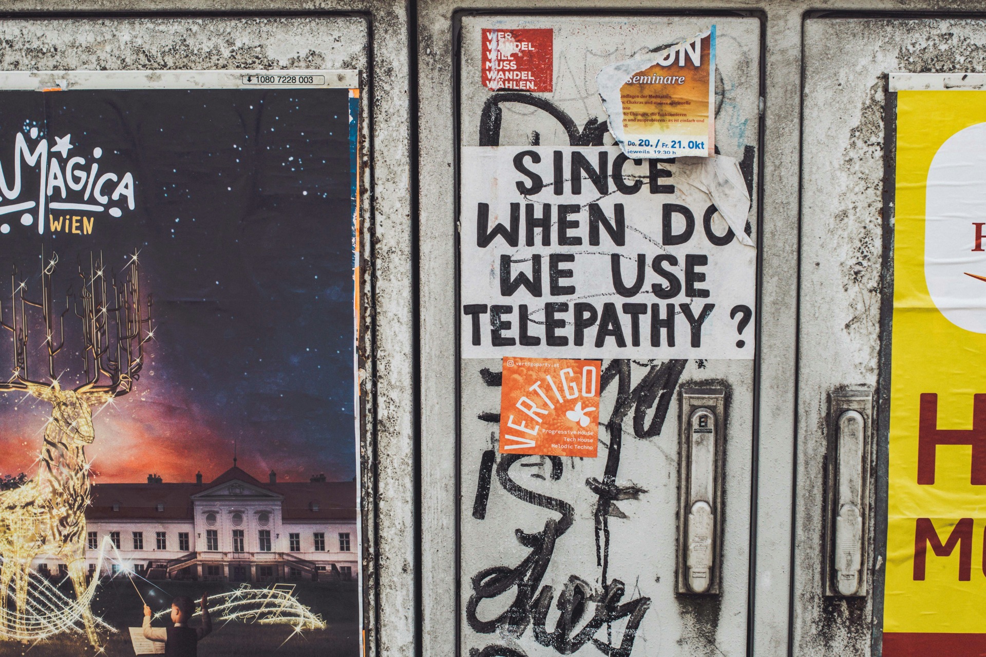 Affiche op een muur waar ook andere affiches ophangen. Tekst op de affiche: Since when do we use telepathy?'