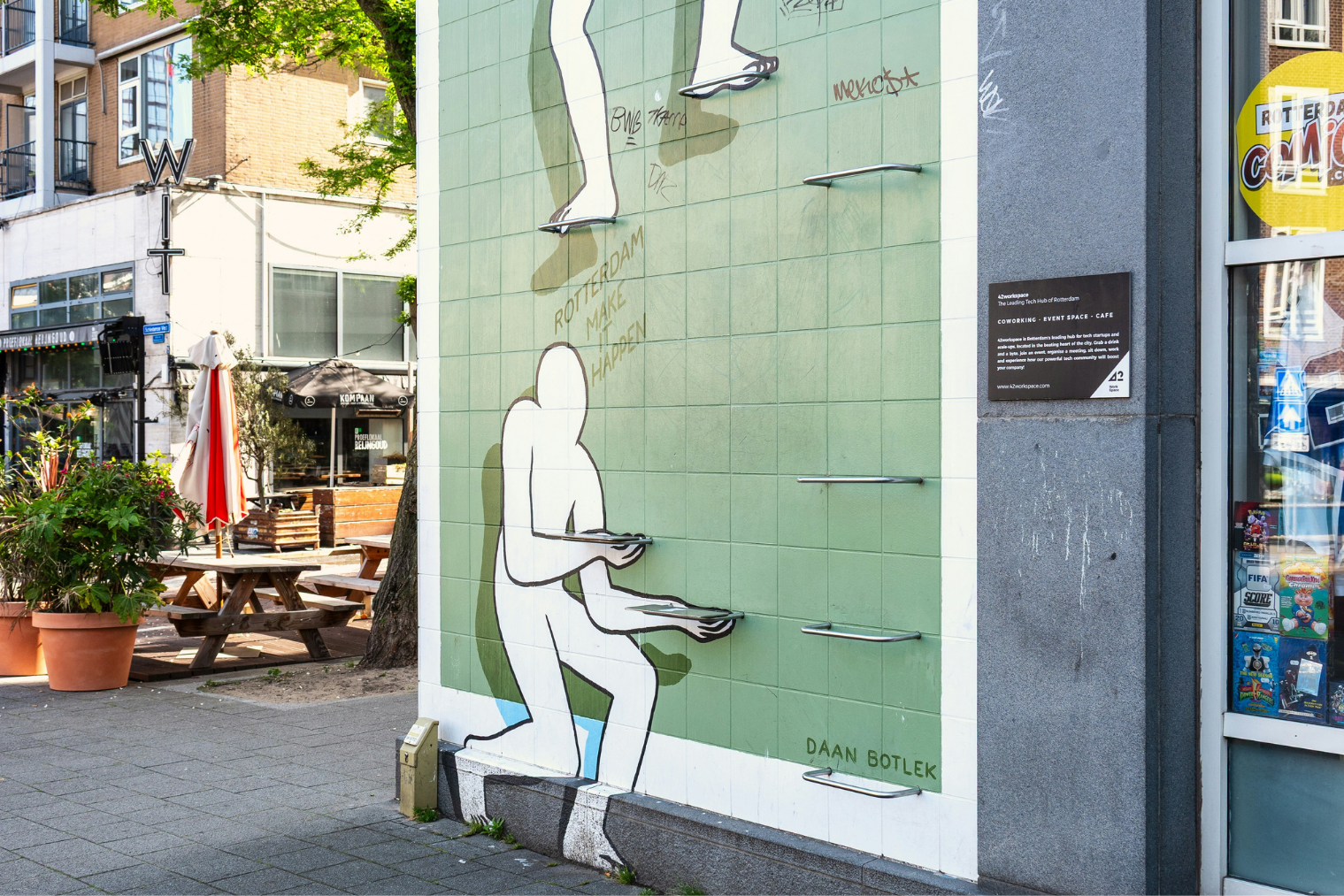 Muurschildering mensachtig figuur die trapjes in een muur vasthoudt en ondersteunt waardoor een ander figuur naar boven kan klimmen.